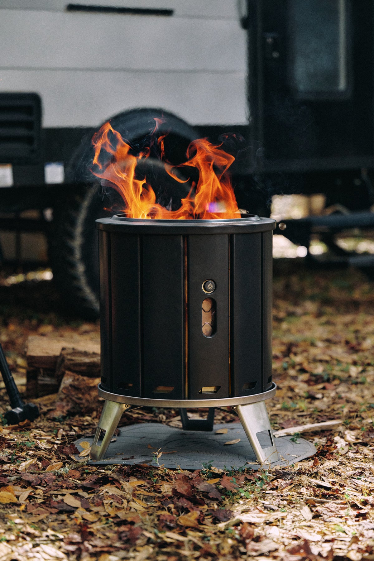 Black fire pit with flames burning on a grassy area