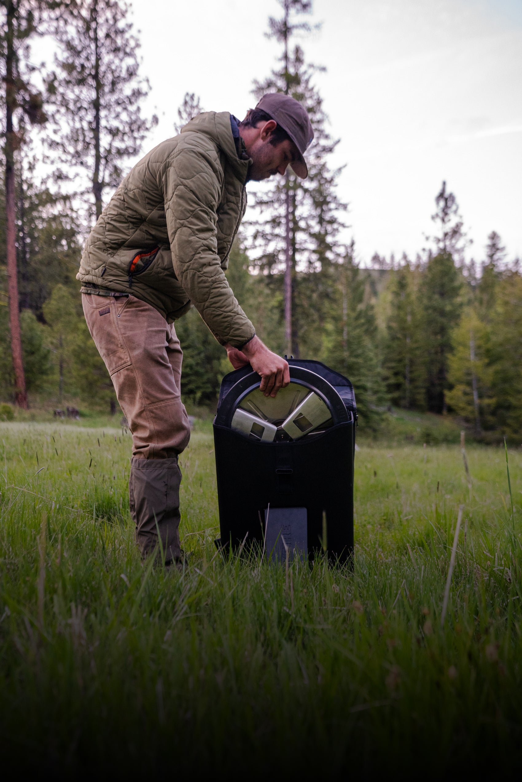 Person in outdoor setting taking a packfire foldable firepit out of it's portable travel case
