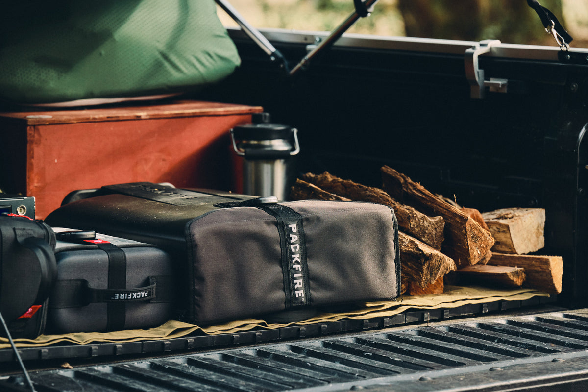 Packfire travel cases in the bed of a truck with firewood stacked beside