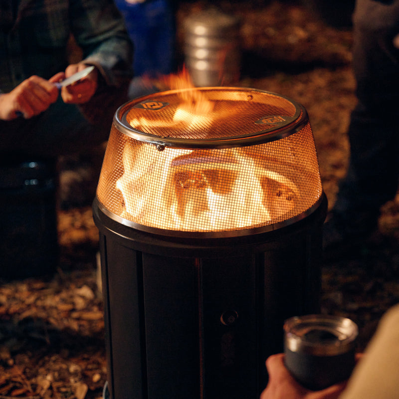 Glowing orange flame inside metal mesh fire pit top with black outer housing